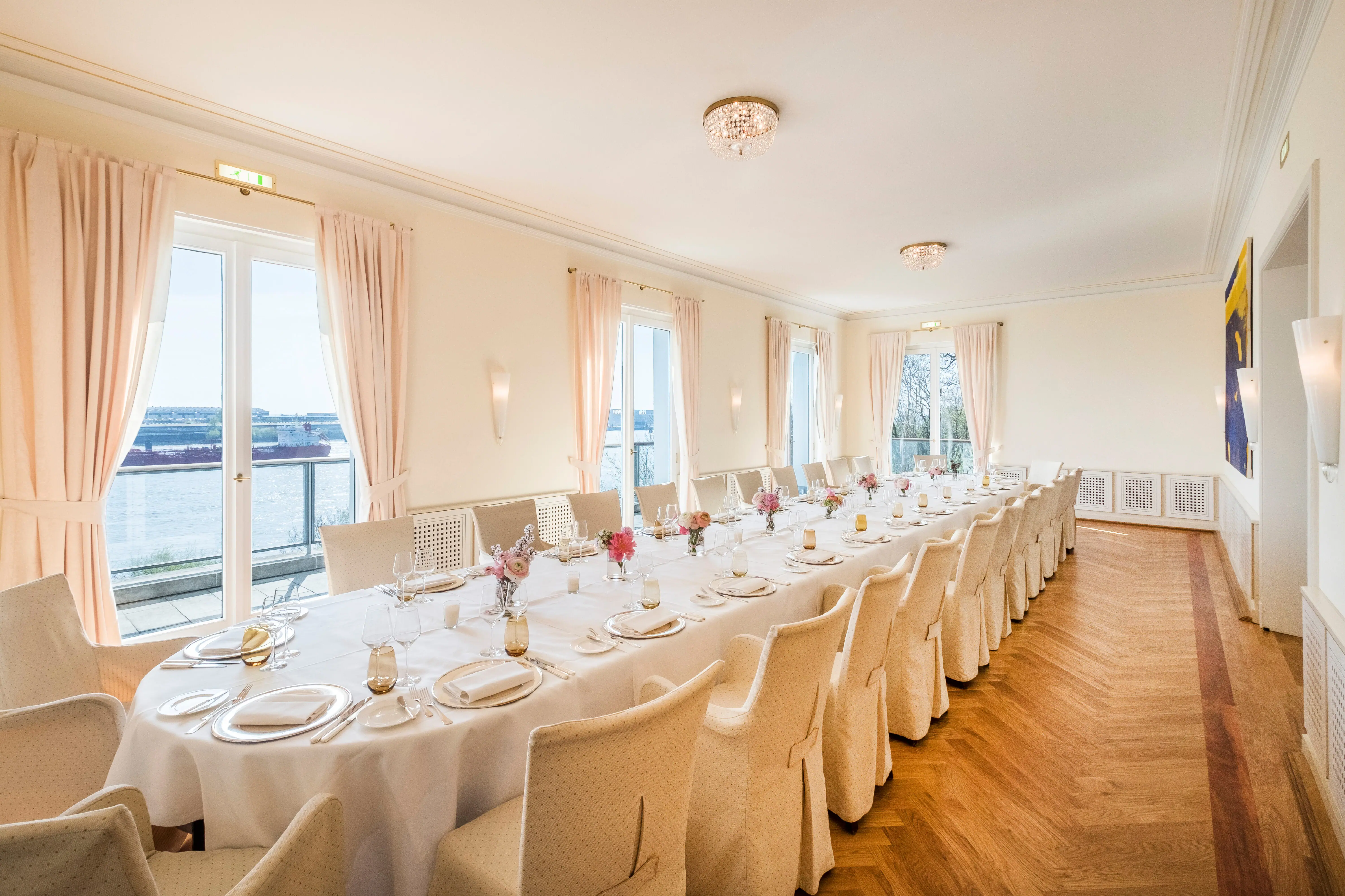 A long table set for a wedding reception indoors with elegant tableware and linens.
