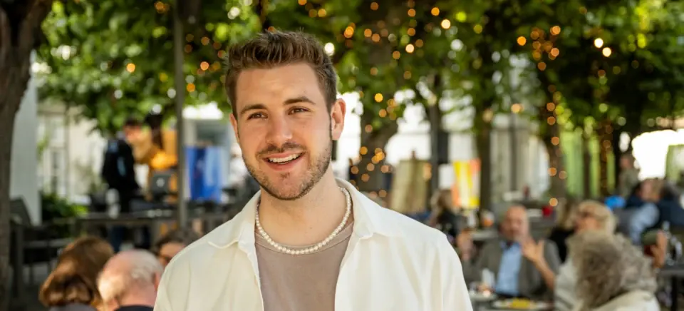 A man smiling at the camera outdoors.
