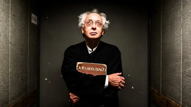 Philippe Herreweghe mit verschränkten Armen lächelt.