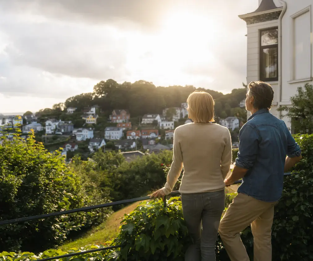 A man and woman standing on a railing overlooking a town.