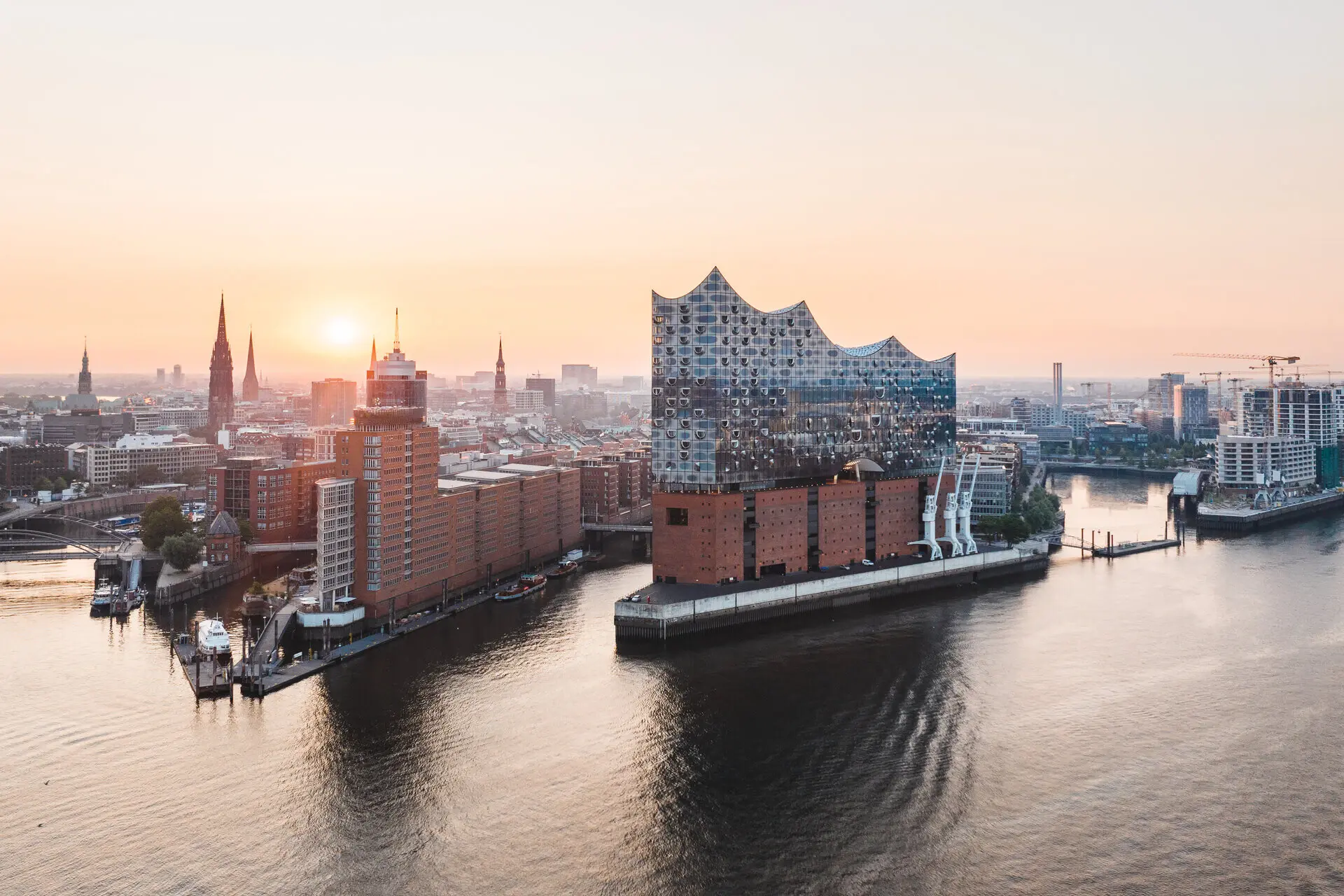 Elbphillharmonie Hamburg City skyline at sunset with a body of water in the foreground.