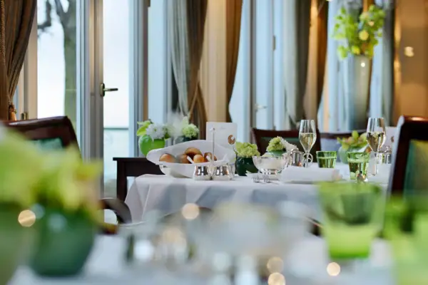 Jacobs Restaurant A table set for a dinner party with elegant tableware, a tablecloth, a floral centerpiece, and wine glasses.