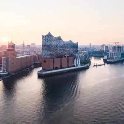Elbphilharmonie A town with a river and buildings; in the foreground, a boat on the water.