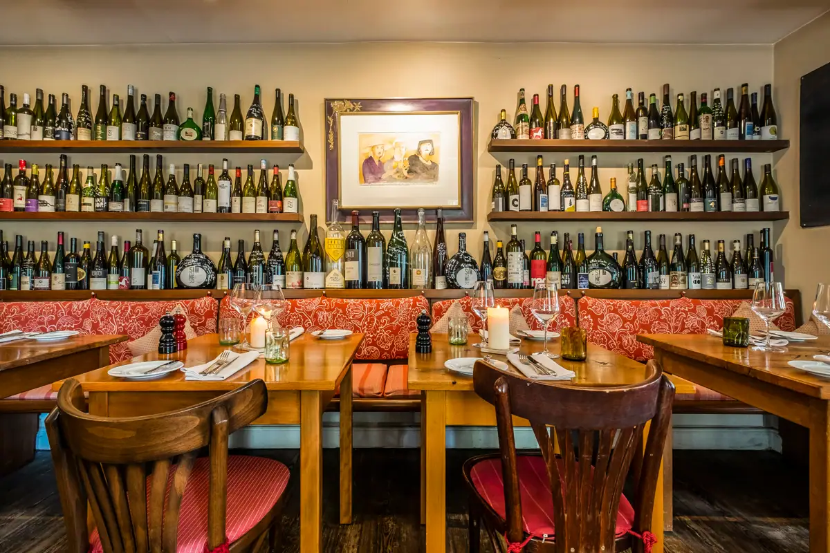 Table with wine bottles displayed on the wall.