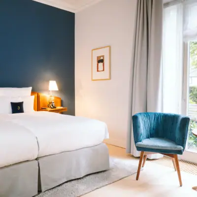 Ein helles Hotelzimmer mit gemütlichem Bett und blauen Akzenten.
