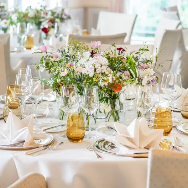 A festively decorated table with a floral arrangement and wine glasses.