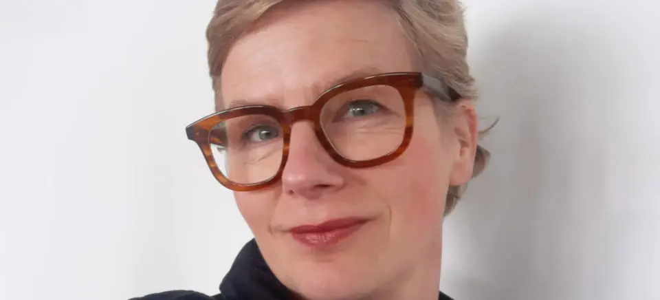 A woman wearing glasses and smiling.