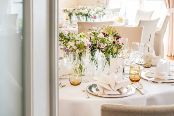 Ein festlich geschmückter Tisch mit Blumenarrangement und Weingläsern.