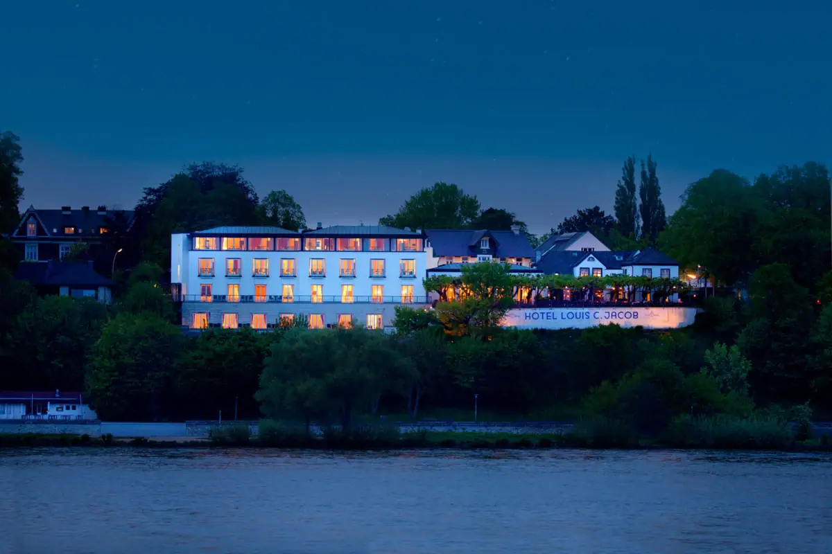 A building with lights on the side of it at night, surrounded by trees and a clear sky.