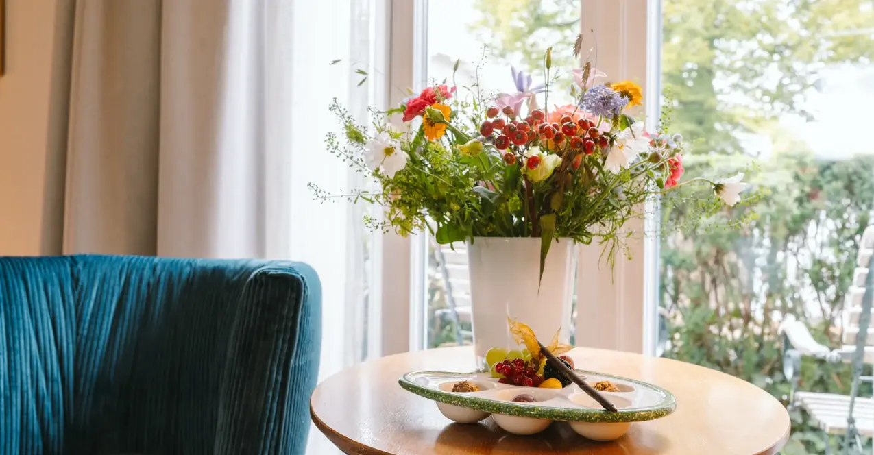 A vase of flowers on a table in a hotel room at the Louis C. Jacob.