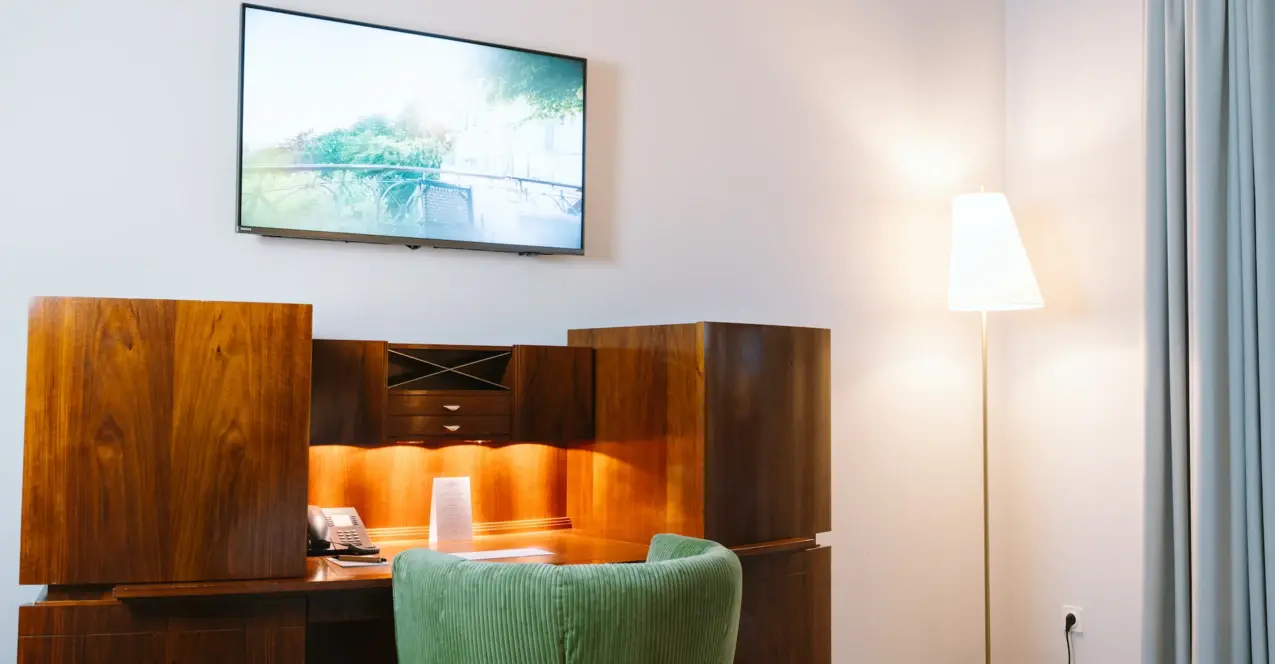 Desk with a television on the wall in a hotel room at the Louis C. Jacob Hamburg.