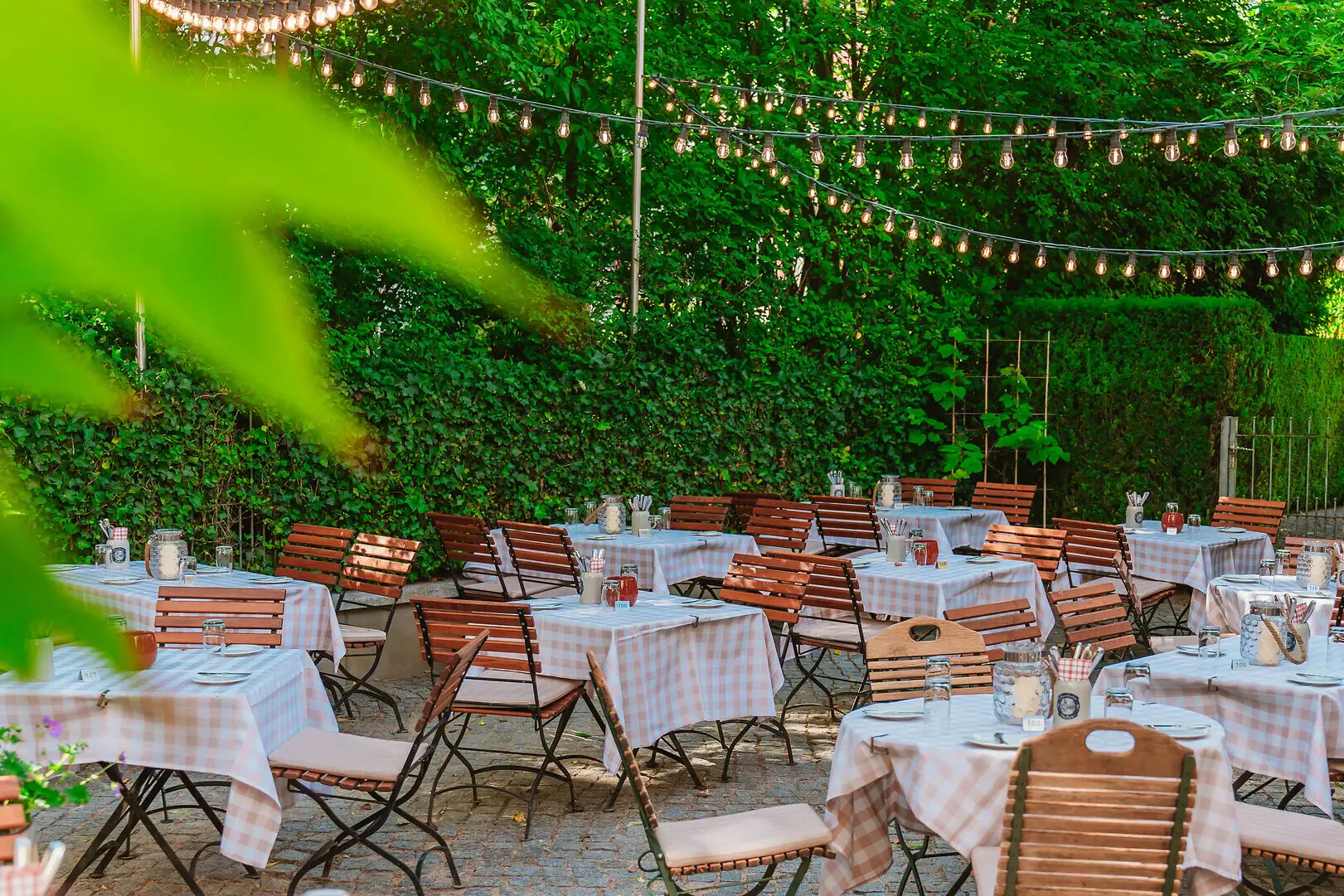Beergarden Kleine Jacob Outdoor dining area with tables and chairs under string lights.