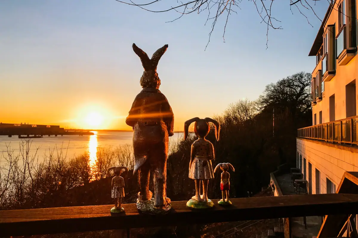 Easter bunny figures stand on the railing of the Lindenterrasse at the Hotel Louis C. Jacob with a view of the setting sun over the Elbe.