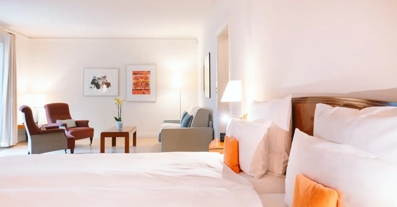 Interior view of a hotel room with a bed and chairs.