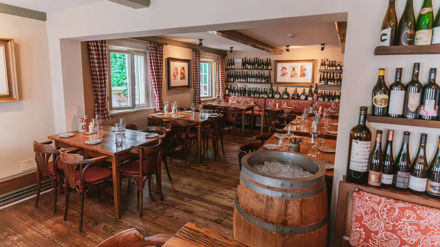 Interior view of a dining room with tables, chairs and bottles of wine.