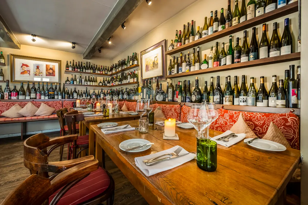 Kleine Jacob Table with wine bottles displayed on the wall.