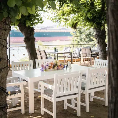 A table and chairs under trees providing shade.