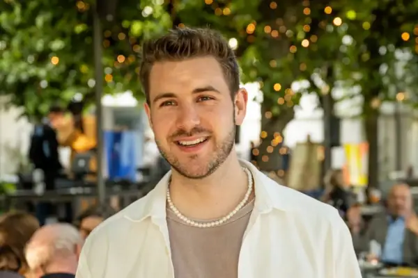 Luk Schäfer Ein junger Mann mit leichtem Bart lächelt in die Kamera.