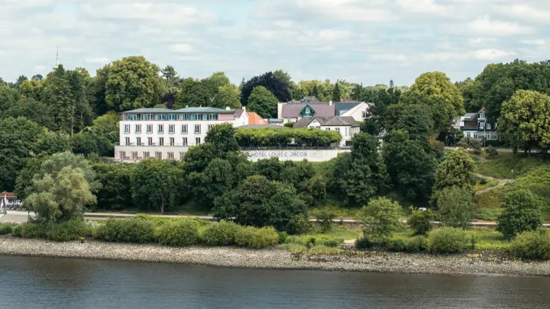 Building near a body of water with trees and clouds in the sky.