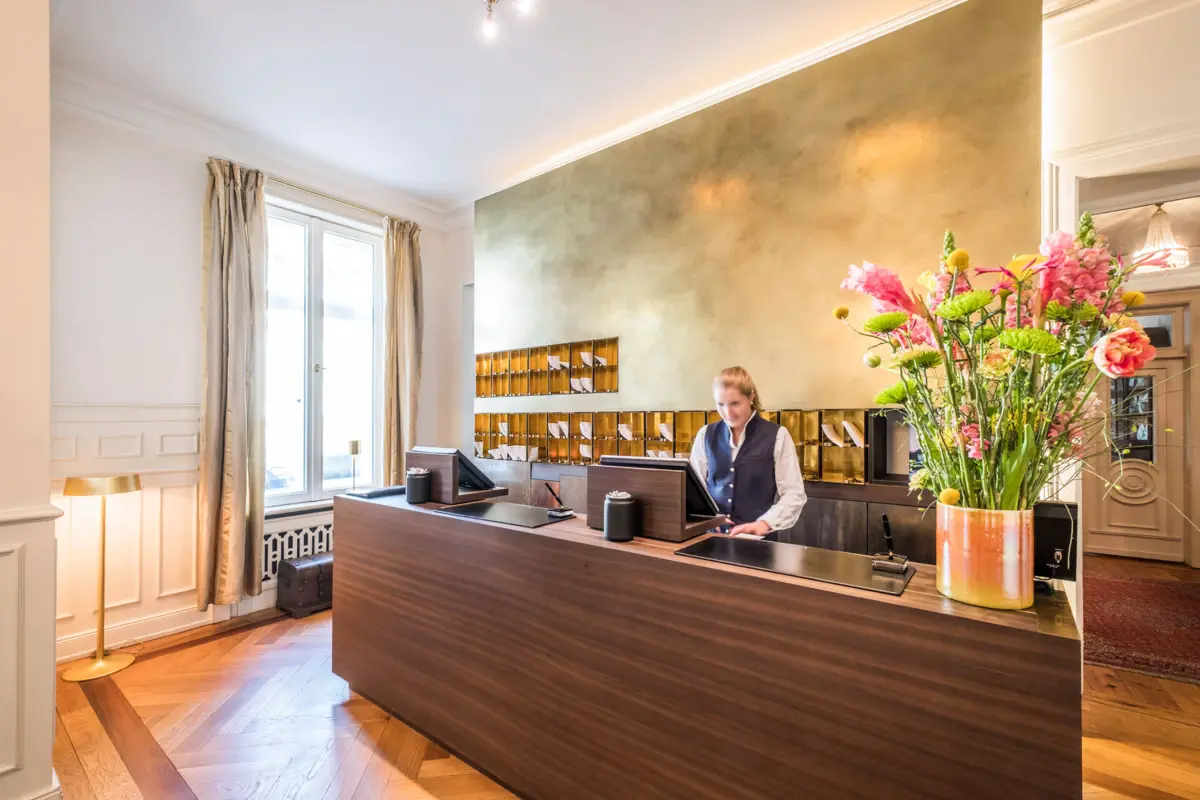 Eine Mitarbeiterin steht hinter dem Empfangstresen im Hotel Louis C. Jacob.