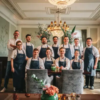 A group of people wearing aprons, smiling and posing for a photo indoors.