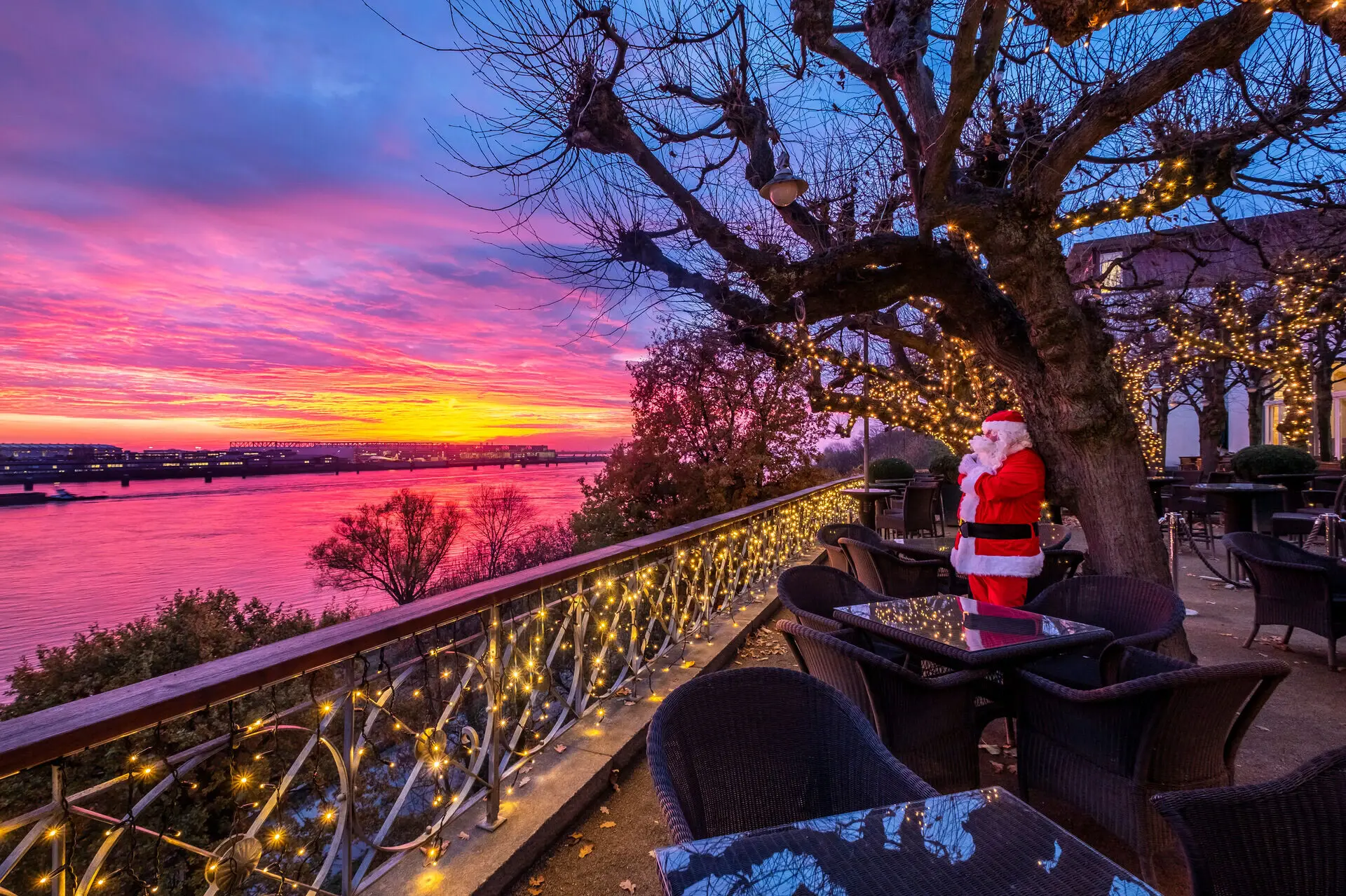 Lindenterrasse Weihnachten Ein Weihnachtsmann steht auf der Lindenterrasse und das Geländer ist mit Lichterketten geschmückt.
