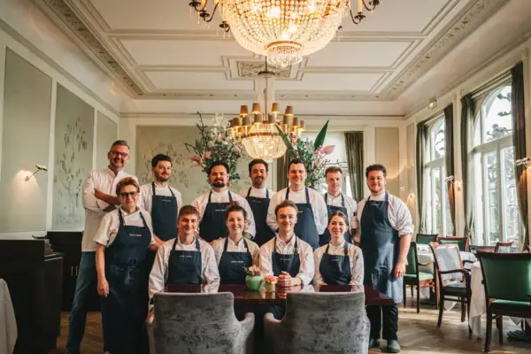 A group of people wearing aprons posing for a photo indoors.