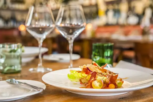 A plate of food with a wine glass on a table.
