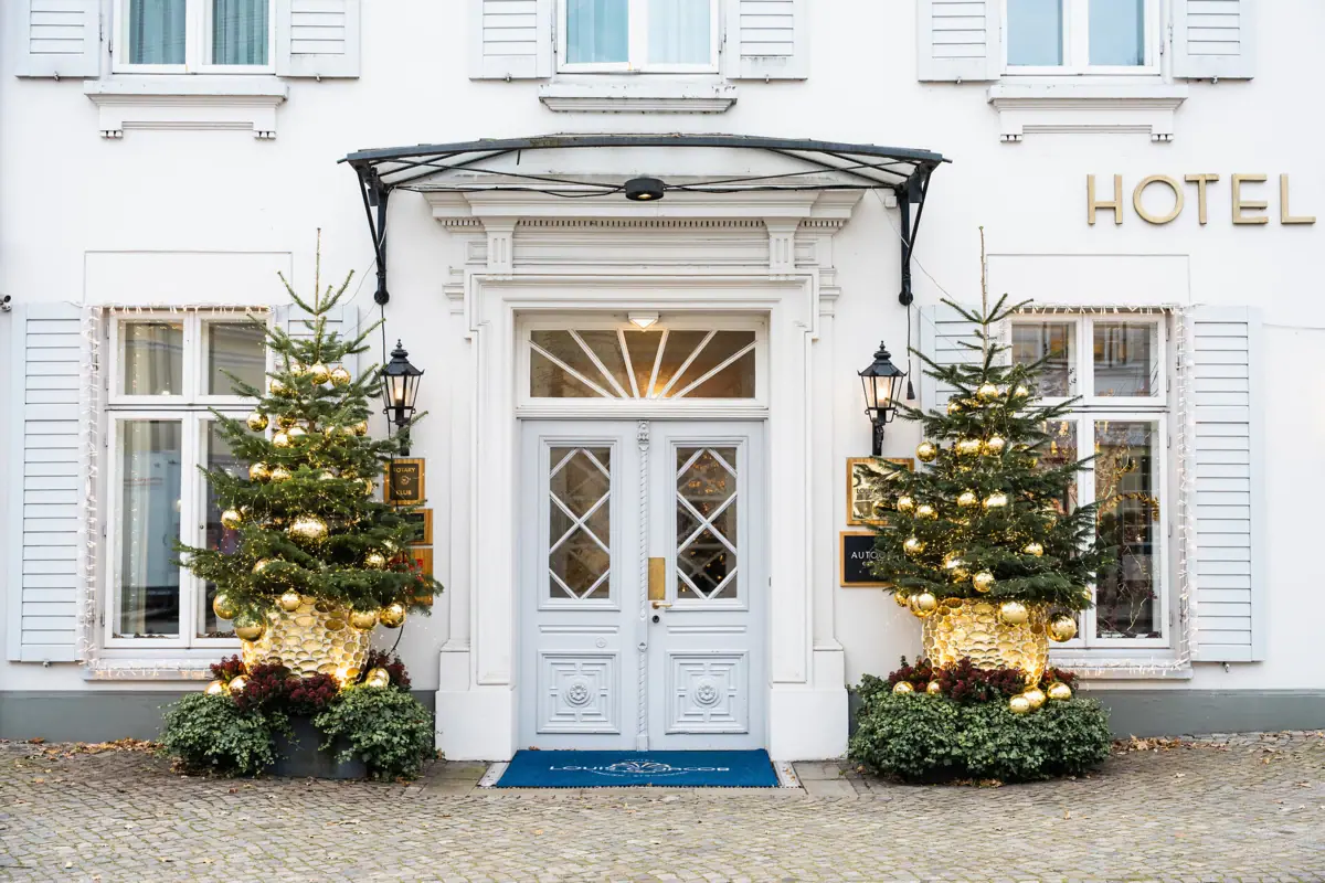 A white building with Christmas trees and fairy lights.