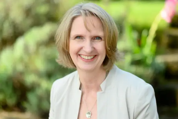 Astrid Krömer Eine Frau mit hellen Haaren trägt einen hellen Blazer und lächelt in die Kamera.