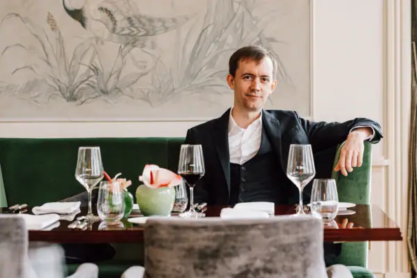 A man sitting at a table with wine glasses.