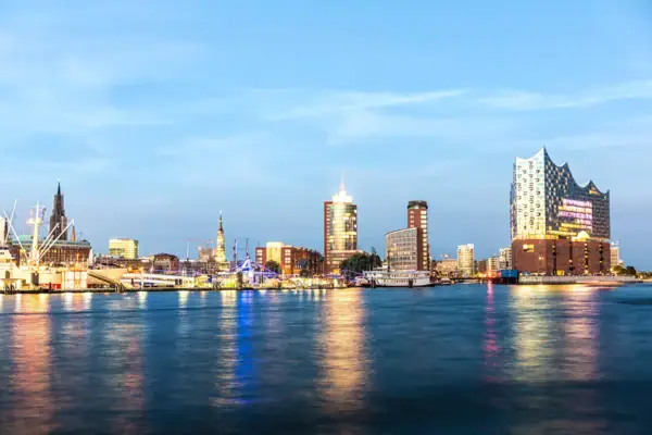 Blick von der Elbe aus auf den beleuchteten Hamburger Hafen und die Elbphilharmonie.