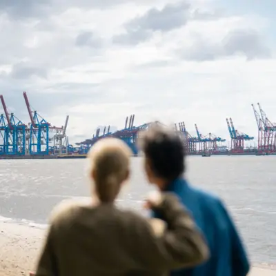 A man and woman looking at a large body of water under a cloudy sky.