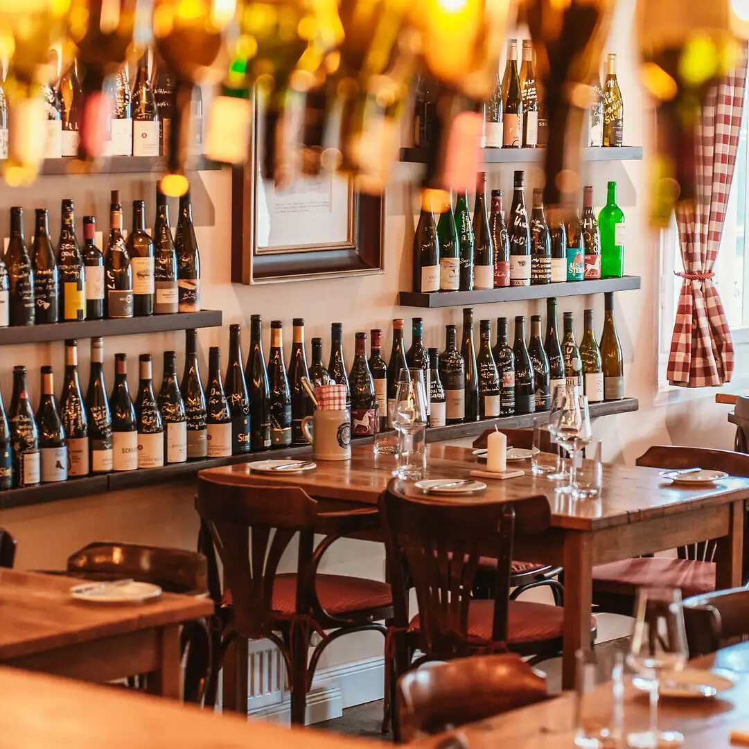 A room with tables and chairs featuring bottles of wine.