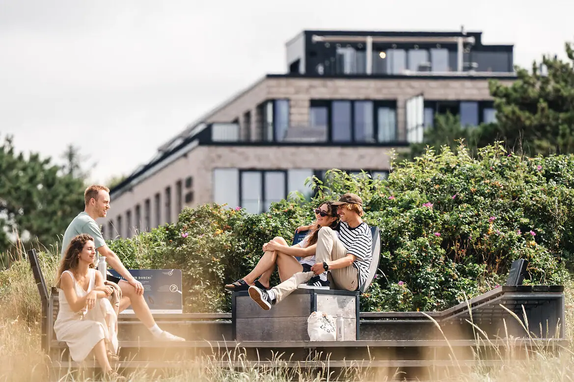 A group of people are sitting on a bench outside.