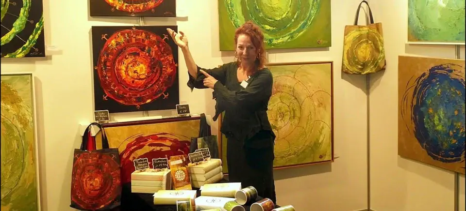 A woman standing in front of a table with paintings.