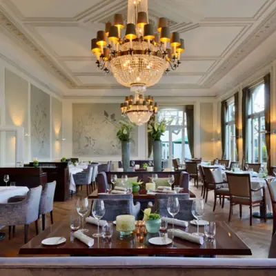 A room with tables, chairs and chandeliers.