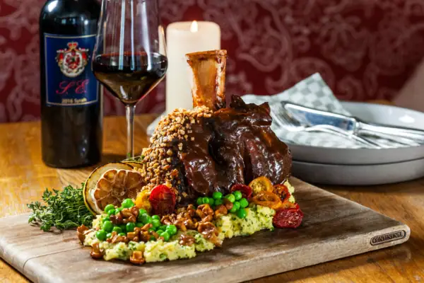 A plate of food on a table with a glass bottle nearby.
