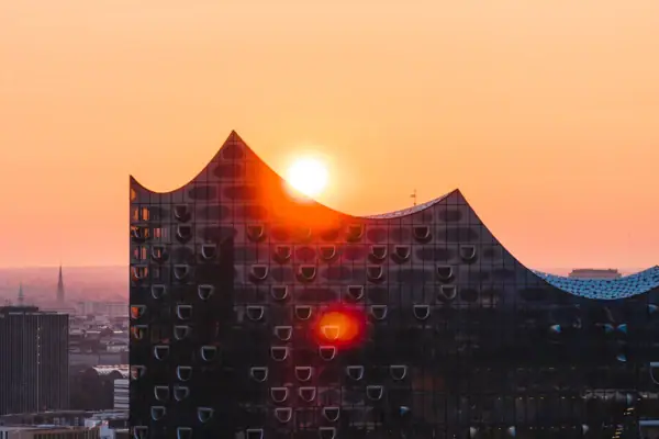 Sun setting over a building with a colorful sky.