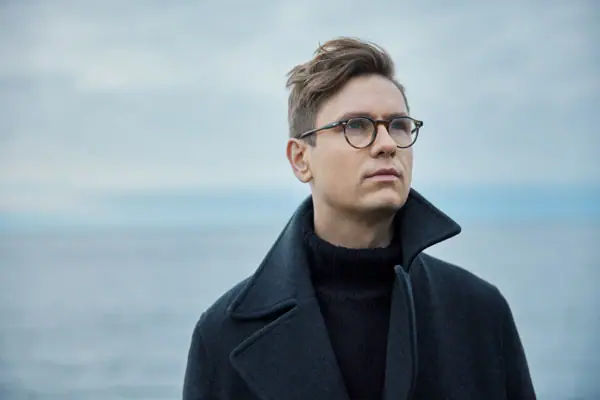 Víkingur Ólafsson A man wearing glasses and a coat.