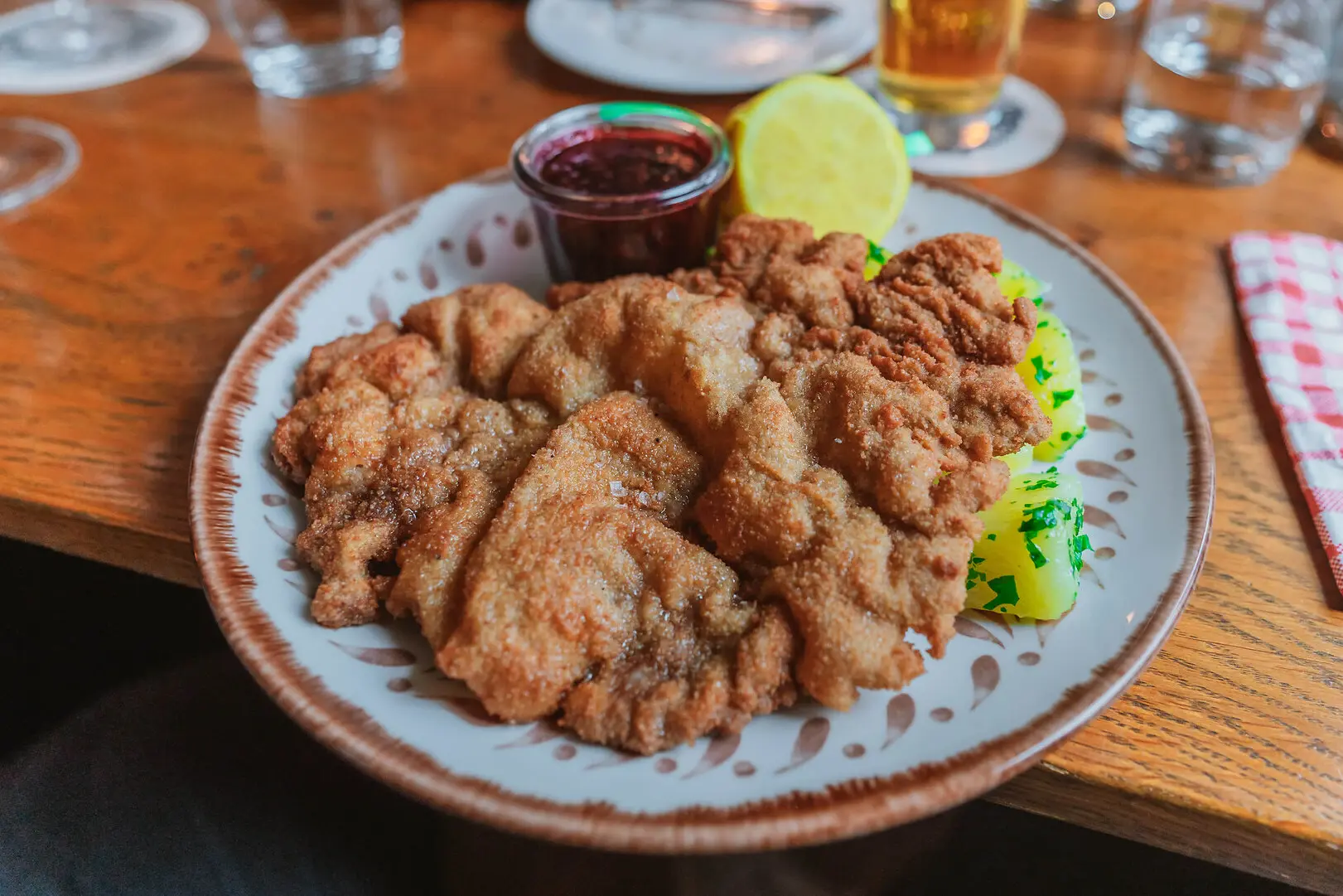 Original Wiener Schnitzel A plate of fried Schnitzel with a lemon wedge and dipping sauce.