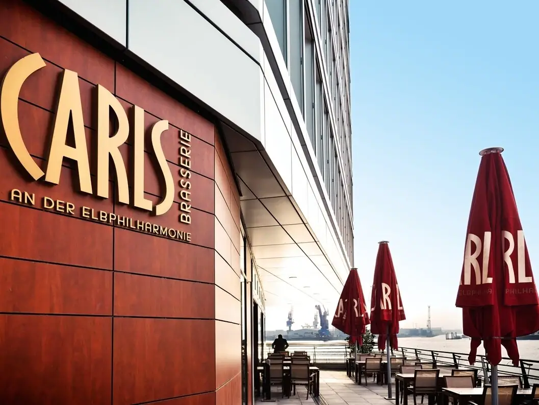 CARLS Restaurant Hamburg Das CARLS Restaurant an der Elbphilharmonie mit Tischen und Stühlen im Freien.