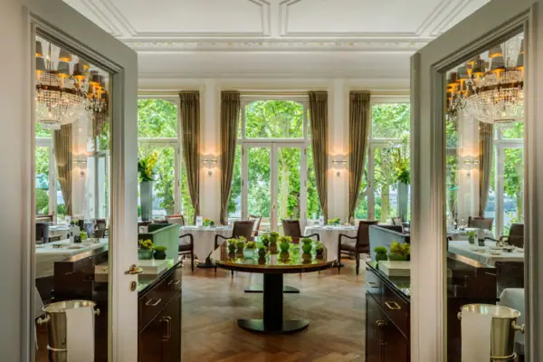 Saal des Jacobs Restaurants mit Tischen, Stühlen, Kronleuchtern und Fenstern.