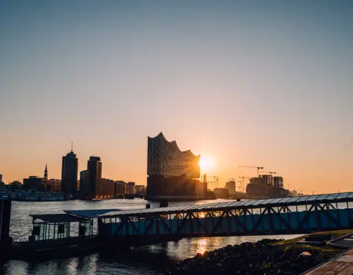Mit Blick über die Elbe ist die Elbphilharmonie zu sehen, hinter der die Sonne aufgeht. 