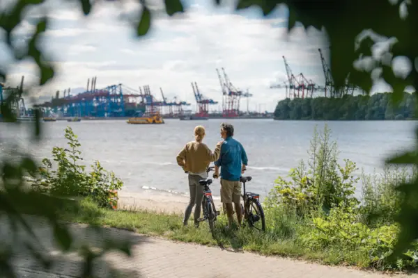 A man and a woman are standing next to some bicycles by a body of water.