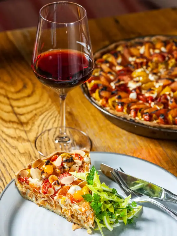 A glass of wine next to a plate of food on a table.