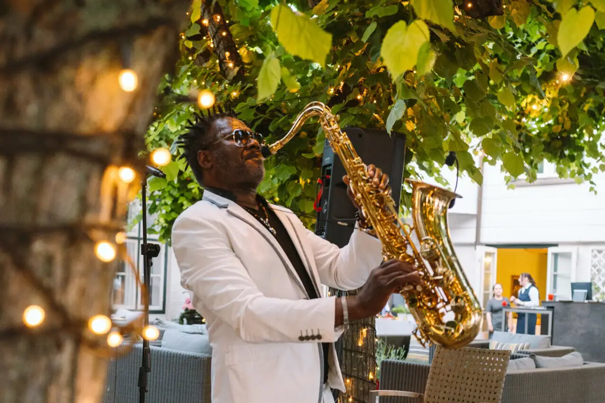 A man playing a saxophone under a tree.