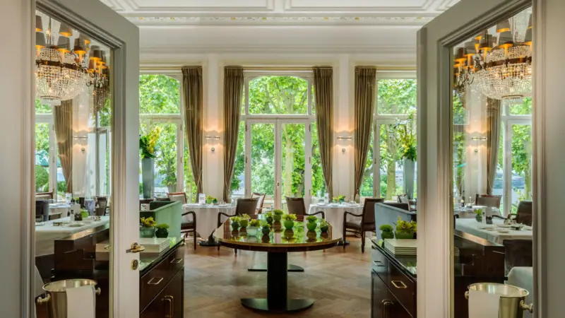 A room with tables, chairs, and a large window.