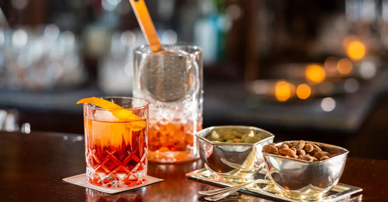 A cocktail and a plate of food on a table.