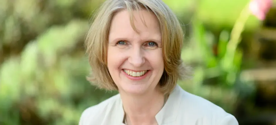A woman smiling outdoors for a portrait photograph.